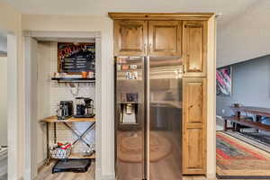 Kitchen with a textured ceiling, light wood-type flooring, and stainless steel fridge with ice dispenser