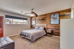 Carpeted bedroom with ceiling fan and wood walls