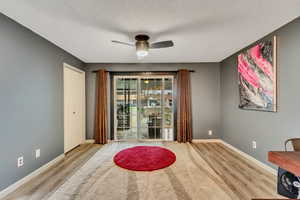 Living area featuring ceiling fan, a textured ceiling, and light wood-type flooring