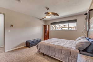 Bedroom featuring ceiling fan, carpet flooring, and a textured ceiling