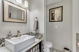 Bathroom featuring vanity, decorative backsplash, and toilet