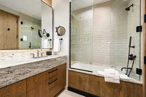 Bathroom with vanity and combined bath / shower with glass door