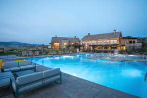 Pool at dusk featuring a mountain view, a patio area, and a hot tub