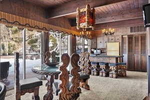 Carpeted dining room featuring beam ceiling, wooden walls, and wooden ceiling