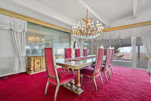 Carpeted dining room with an inviting chandelier and lofted ceiling with beams