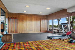 Exercise area featuring wooden walls and a textured ceiling