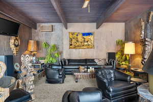 Carpeted living room featuring beam ceiling and wooden ceiling