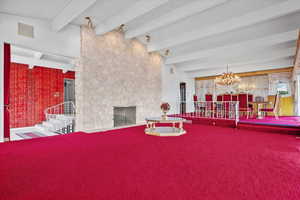 Dining room with beamed ceiling, carpet flooring, a fireplace, and an inviting chandelier