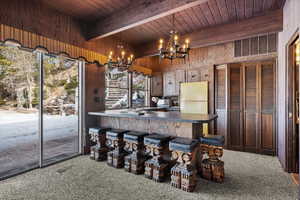 Kitchen with an inviting chandelier, wood ceiling, refrigerator, hanging light fixtures, and wooden walls