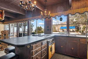 Kitchen featuring wall oven, decorative light fixtures, wooden ceiling, kitchen peninsula, and a chandelier