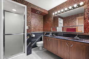 Bathroom featuring a shower with door, vanity, tile patterned floors, and toilet