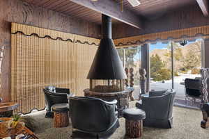 Living area with beamed ceiling, carpet floors, wood ceiling, and wood walls