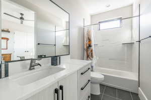 Full bathroom with shower / tub combo with curtain, vanity, ceiling fan, toilet, and tile patterned floors