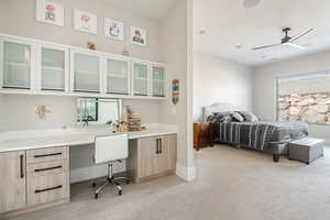 Carpeted bedroom featuring built in desk