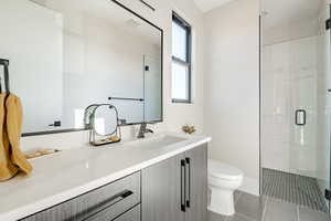 Bathroom with vanity, a shower with shower door, tile patterned floors, and toilet