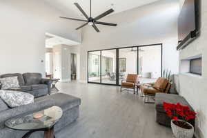 Living room featuring a fireplace, ceiling fan, and light hardwood / wood-style flooring