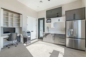 Kitchen featuring white cabinetry, sink, a breakfast bar area, stainless steel refrigerator with ice dispenser, and dark brown cabinets