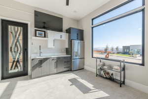 Kitchen with white cabinetry, stainless steel refrigerator with ice dispenser, sink, and ceiling fan