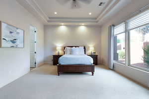 Bedroom with a raised ceiling and light carpet