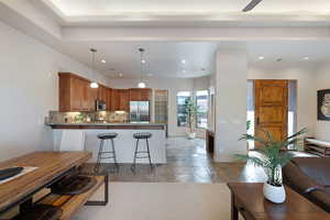 Kitchen featuring a kitchen bar, tasteful backsplash, kitchen peninsula, pendant lighting, and stainless steel appliances