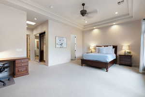 Carpeted bedroom with a tray ceiling and ceiling fan