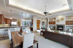 Dining space featuring ceiling fan, a tray ceiling, a fireplace, and built in shelves