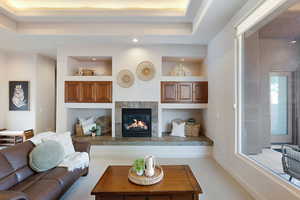 Carpeted living room with a tray ceiling and a tiled fireplace