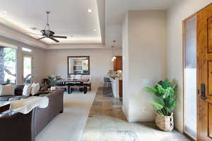 Living room featuring a raised ceiling and ceiling fan