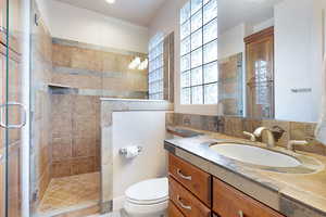 Bathroom with vanity, toilet, and a shower with shower door