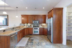 Kitchen featuring sink, kitchen peninsula, pendant lighting, stainless steel appliances, and backsplash