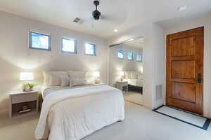 Bedroom with light colored carpet, ceiling fan, and a closet