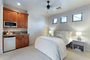 Bedroom with sink, light carpet, stainless steel fridge, and ceiling fan