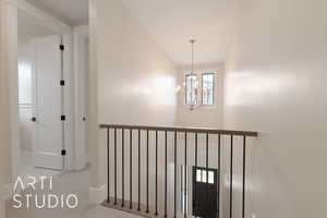 Hallway featuring a notable chandelier and light colored carpet