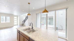 Kitchen featuring sink, decorative light fixtures, light hardwood / wood-style flooring, and a textured ceiling