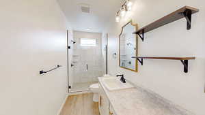 Bathroom with hardwood / wood-style floors, an enclosed shower, vanity, a textured ceiling, and toilet