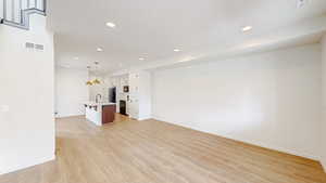 Unfurnished living room featuring sink and light hardwood / wood-style flooring