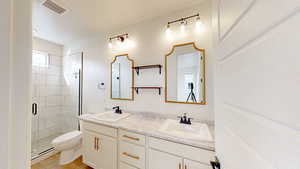 Bathroom featuring toilet, baseboard heating, vanity, a shower with door, and hardwood / wood-style flooring