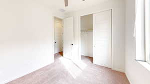 Unfurnished bedroom featuring light carpet, a closet, and ceiling fan