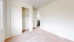 Unfurnished bedroom featuring light carpet and a closet