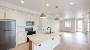 Kitchen featuring white cabinetry, hanging light fixtures, black appliances, and sink