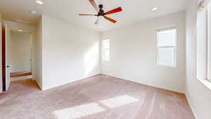 Empty room featuring light colored carpet and ceiling fan