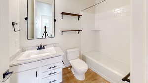 Full bathroom featuring vanity, wood-type flooring, bathtub / shower combination, and toilet