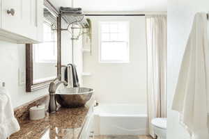 Full bathroom featuring vanity, shower / bath combination with curtain, and toilet