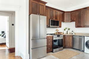 Kitchen featuring appliances with stainless steel finishes, washer / dryer, and light stone countertops