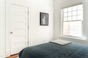 Bedroom with hardwood / wood-style floors and multiple windows