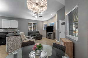 Living room with an inviting chandelier, lofted ceiling, and light hardwood / wood-style flooring