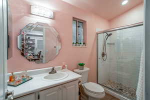 Bathroom featuring an enclosed shower, vanity, and toilet