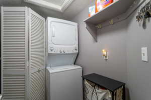 Clothes washing area featuring stacked washer and clothes dryer