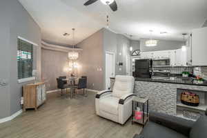 Kitchen with white cabinetry, stainless steel appliances, decorative light fixtures, and light hardwood / wood-style flooring