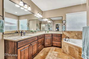 Bathroom featuring tiled tub and vanity